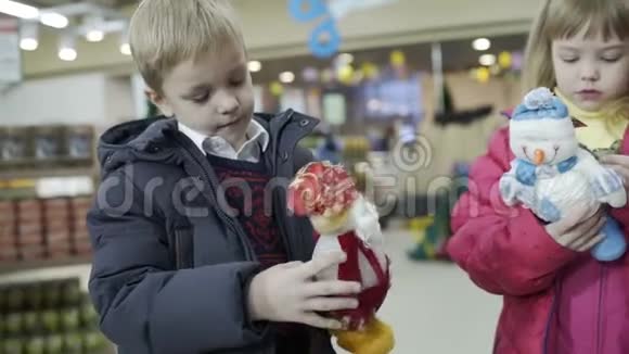 可爱的女孩和男孩选择玩具装饰圣诞树在购物中心视频的预览图