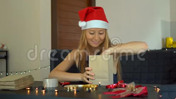 一个年轻的女人打包礼物现在用手工纸包裹上面有红色和金色的丝带供圣诞节或新年使用视频的预览图