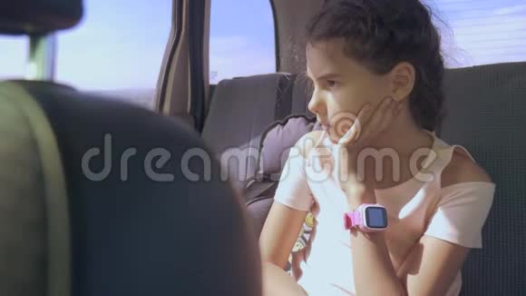悲伤的女孩无聊地坐在后座的车里小女孩在车里无聊长途旅行视频的预览图