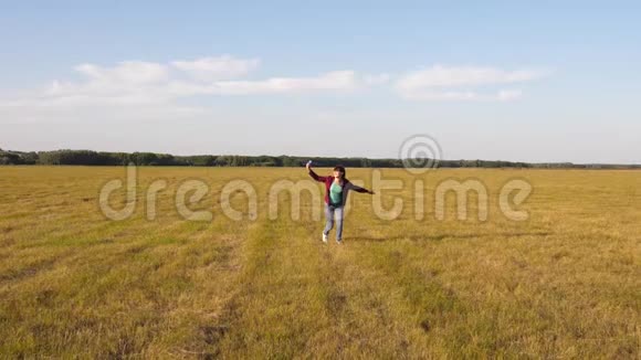 青少年梦想飞行和成为飞行员快乐的女孩带着玩具飞机在夕阳下的田野上奔跑视频的预览图