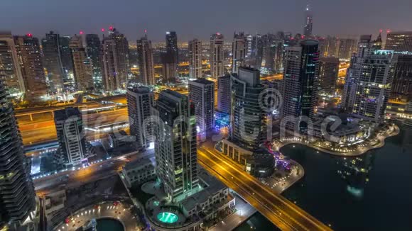从空中俯瞰迪拜码头的夜晚到白天现代化的塔楼和道路上的交通视频的预览图