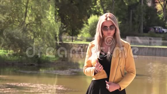 穿着黄色夹克和太阳镜的金发美女视频的预览图