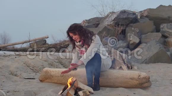晚上坐在火炉旁的年轻女子火视频的预览图