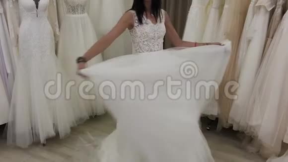 美丽的女孩在新娘沙龙里测量婚纱视频的预览图