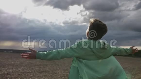 男孩向天空举起双手看着太阳刮风的天气视频的预览图