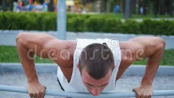 在城市公园的运动场上做俯卧撑的运动员强壮的年轻肌肉男夏季户外训练视频的预览图
