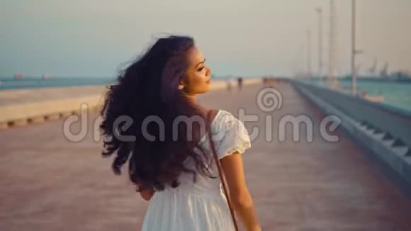 穿着白色裙子的漂亮女孩走在海滨长廊上视频的预览图