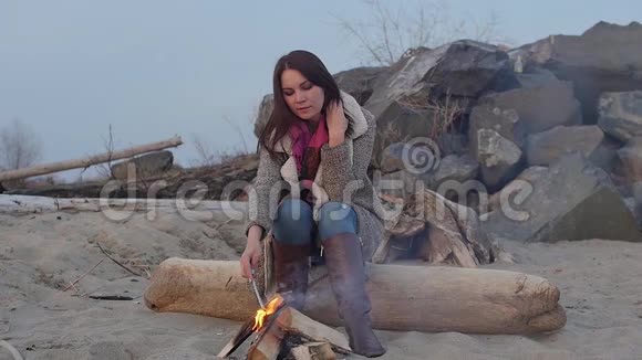晚上坐在火炉旁的年轻女子火视频的预览图
