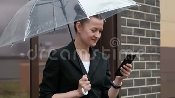 年轻迷人的女人穿着黑色夹克和蓝色牛仔裤在建筑背景下户外摆姿势视频的预览图