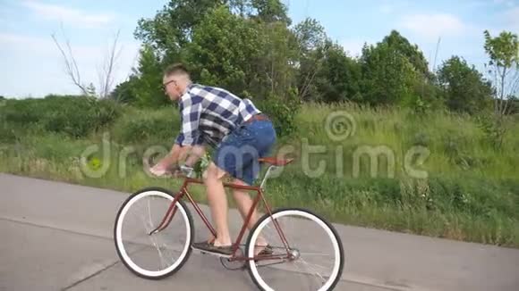 年轻英俊的男子骑着老式自行车在乡村道路上运动男在赛道上骑自行车骑自行车的男性视频的预览图