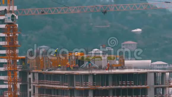 建筑工地的建筑工人建筑工地上的起重机吊起重物建筑施工视频的预览图
