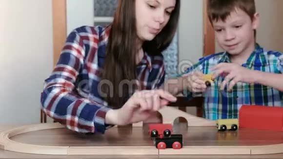 一起玩妈妈和儿子正在玩一条木制铁路坐在桌子旁的火车马车和隧道视频的预览图