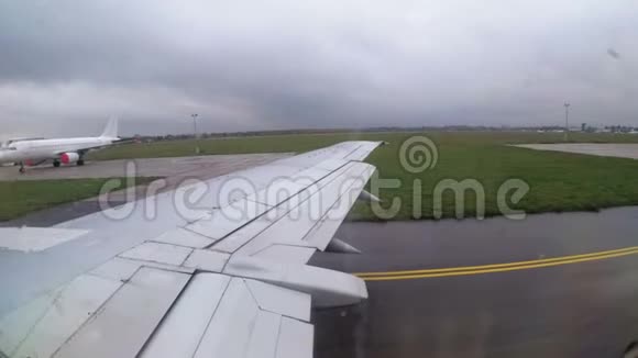 从窗口可以看到机场沿跑道行驶的飞机机翼视频的预览图