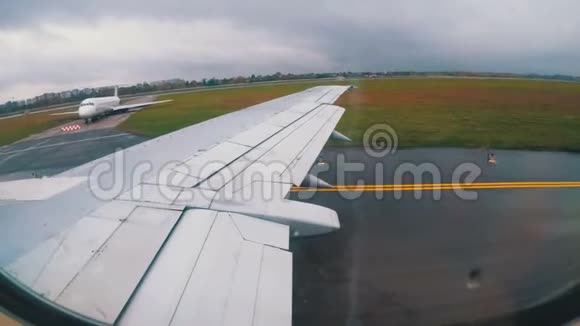 从窗口可以看到机场沿跑道行驶的飞机机翼视频的预览图
