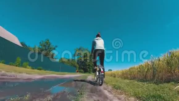在一个村庄的乡村道路上骑着老式自行车的年轻妇女视频的预览图