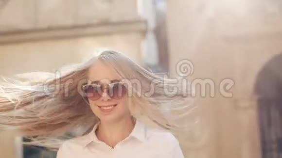 美丽的女人正在摆姿势夏天的下午站在城市的街道上戴墨镜的年轻女子露出牙齿视频的预览图