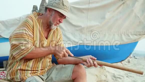 老人坐在海滩上用手做长笛视频的预览图