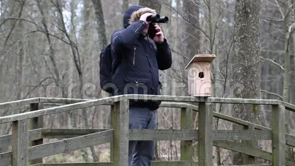 鸟笼附近有望远镜和智能手机的鸟类学家视频的预览图