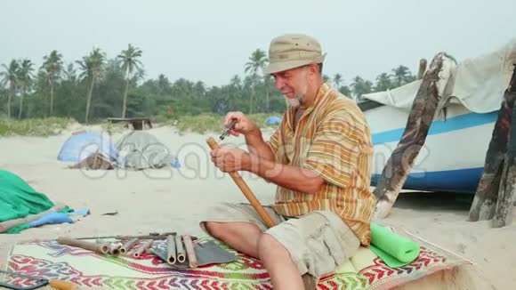 老人坐在海滩上用手做长笛视频的预览图