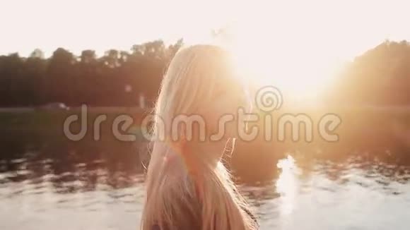 日落时分年轻女孩在河边的草地上摆姿势视频的预览图
