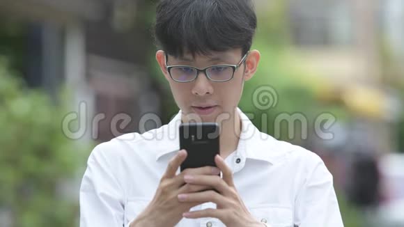 年轻的亚洲商人在户外大街上用电话视频的预览图