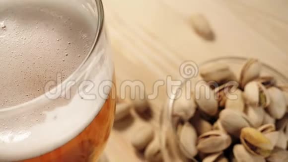 新鲜啤酒玻璃与美味的冷啤酒成木桌的背景上开心果带水的冷鲜啤酒视频的预览图