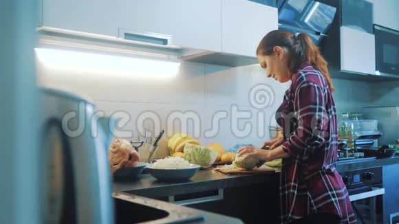 女人在生活方式厨房准备一顿饭的概念厨房里的女孩用刀切卷心菜做素食者视频的预览图