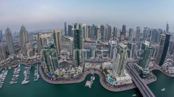 从空中俯瞰迪拜码头白天到晚上的时间现代化的塔楼和道路上的交通视频的预览图