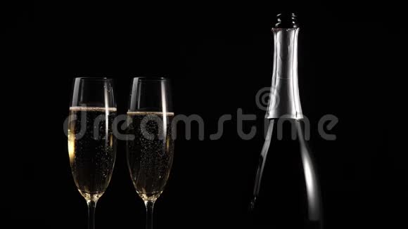 好香槟酒手拿着一杯金色香槟从木桌上放在黑色背景下配有起泡葡萄酒的长笛视频的预览图