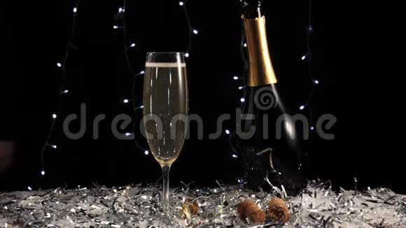 好香槟酒手从桌子上拿一瓶金色的起泡葡萄酒上面放着白雪和彩纸屑视频的预览图