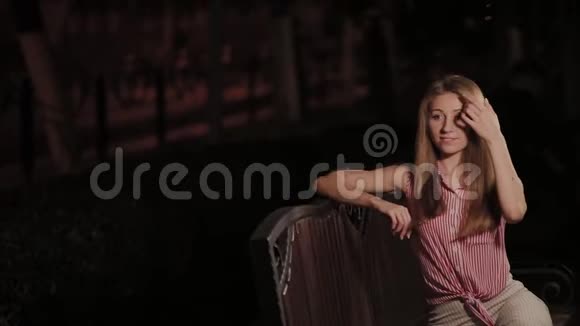 晚上在公园里的长椅上漂亮的年轻女孩视频的预览图