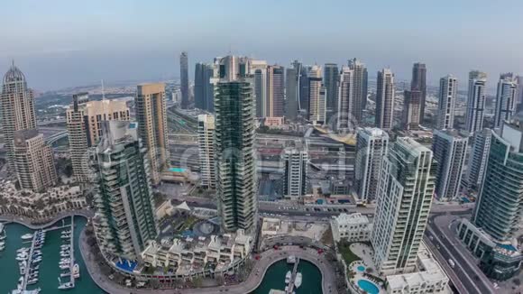 从空中俯瞰迪拜码头白天到晚上的时间现代化的塔楼和道路上的交通视频的预览图