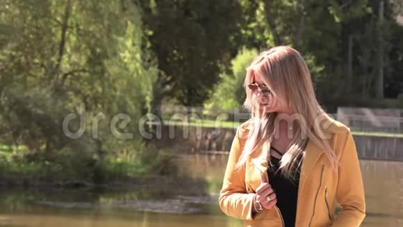 穿着黄色夹克黑色连衣裙和太阳镜的漂亮金发女郎视频的预览图