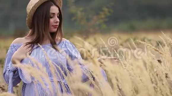大自然中的孕妇试穿针织帽子农场附近的田野和白色农场的背景山岳山岳山岳山岳山岳视频的预览图
