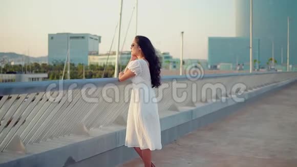 穿着白色裙子的漂亮女孩走在海滨长廊上视频的预览图
