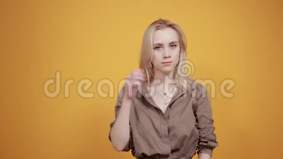棕色上衣的金发女孩在橙色背景下表现出情感视频的预览图