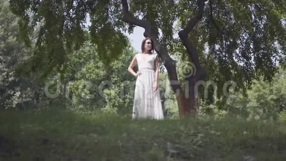 肖像可爱的年轻女孩留着长长的黑发戴着太阳镜穿着一件白色的夏装视频的预览图