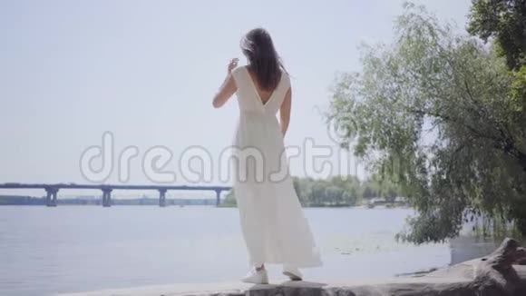 肖像迷人的年轻女孩留着长长的黑发穿着一件白色的夏装站在上面视频的预览图