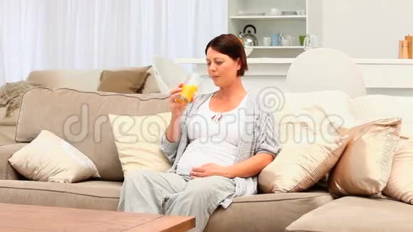怀孕的黑发女人喝了一杯橙汁视频的预览图