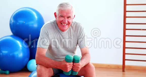 坐在健身球上的老人举重视频的预览图