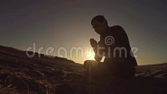 人在夕阳下祈祷神坐剪影阳光宗教视频的预览图
