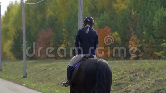 一个年轻的女人骑着一匹黑白马服的马慢慢地骑着一匹马马术比赛之间的中断视频的预览图