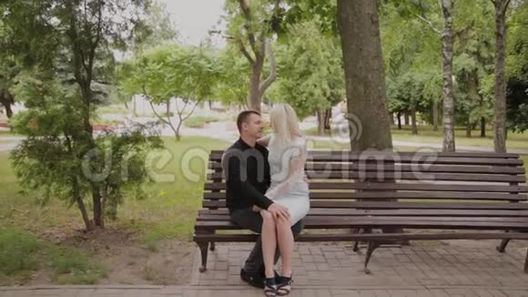 在城市公园里坐在长凳上相爱的幸福夫妇视频的预览图