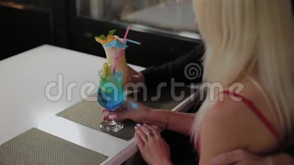 美丽的女孩和男人在晚上的咖啡馆里喝新鲜的鸡尾酒视频的预览图