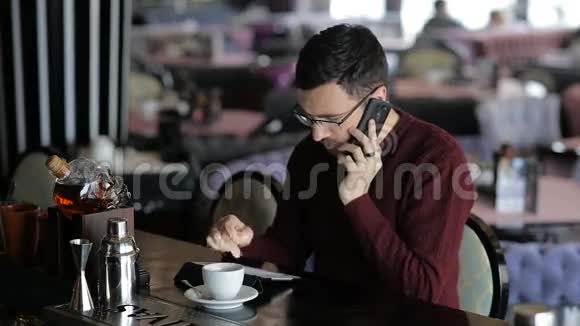 男人在酒吧里用智能手机说话视频的预览图