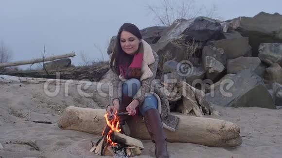 晚火中坐在火炉旁的年轻女子视频的预览图