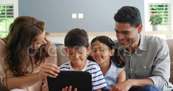 在客厅里使用数码平板电脑的幸福家庭视频的预览图