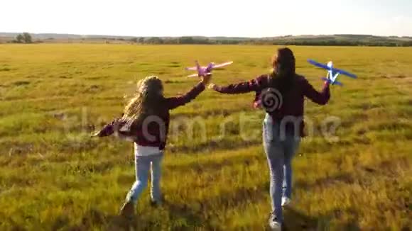 孩子们手里拿着飞机在草地上飞行的梦想快乐童年的概念两个女孩玩视频的预览图