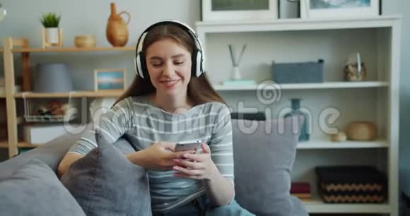 美丽的年轻女子正在用智能手机用耳机听音乐视频的预览图