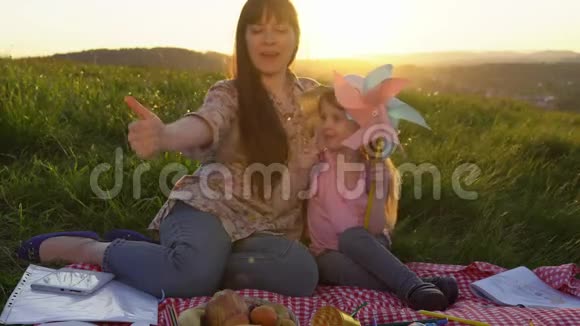 母亲和女儿在日落时在山上野餐视频的预览图